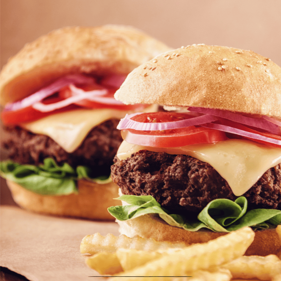 Close up image of oven baked burgers and fries on parchment paper