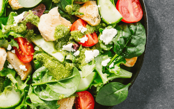 Close up image of a spinach salad in a shallow bowl