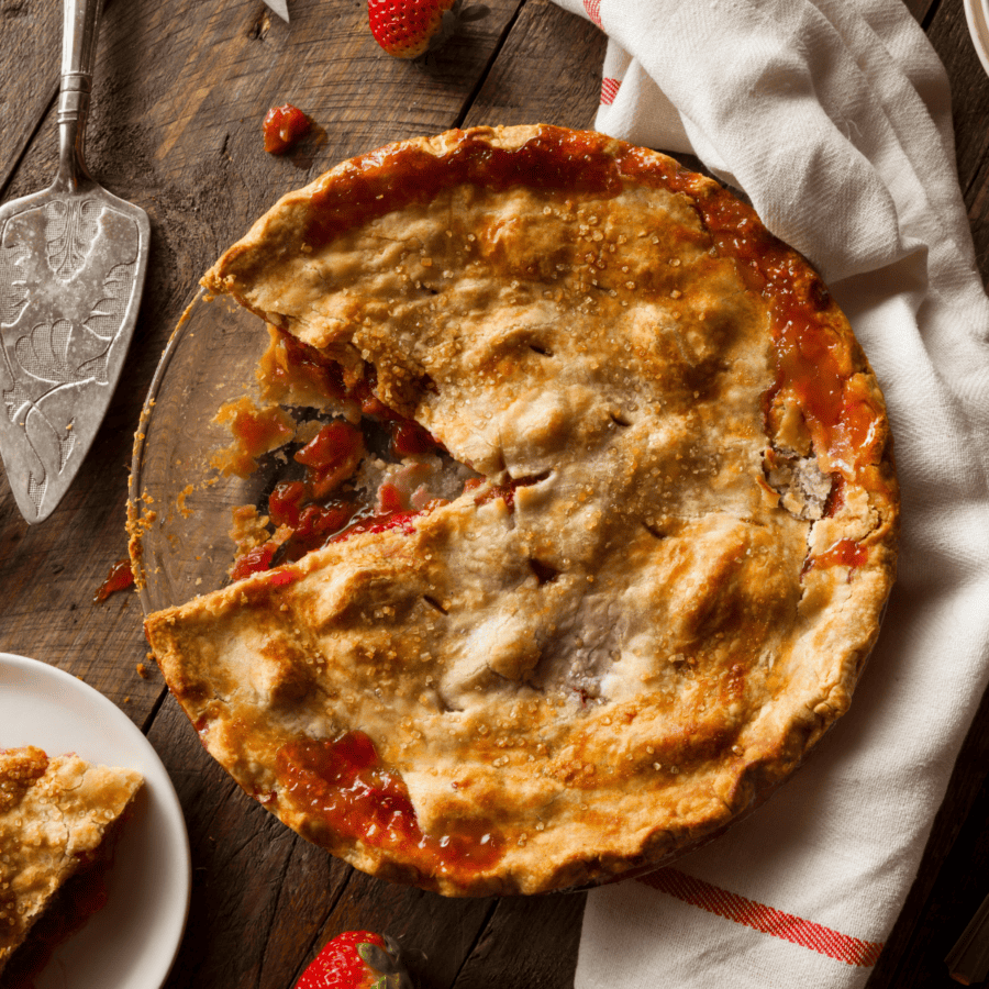 Overhead image of Strawberry Rhubarb Pie on a wooden surface