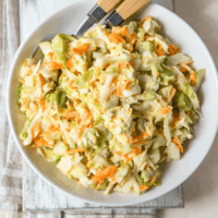 Overhead image of Vegan Coleslaw in a white bowl with utensils