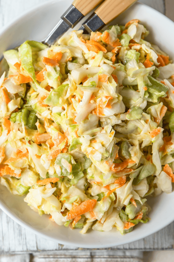 Overhead image of Vegan Coleslaw in a white bowl with utensils
