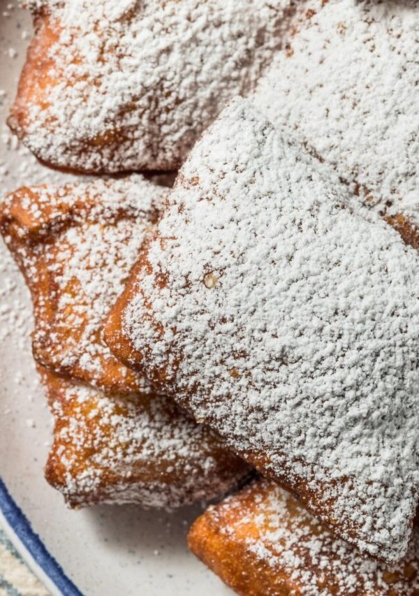 Overhead image of beignets dusted with powdered sugar on a plate