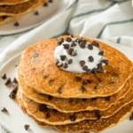 A stack of chocolate chip pancakes with whipped topping - 8
