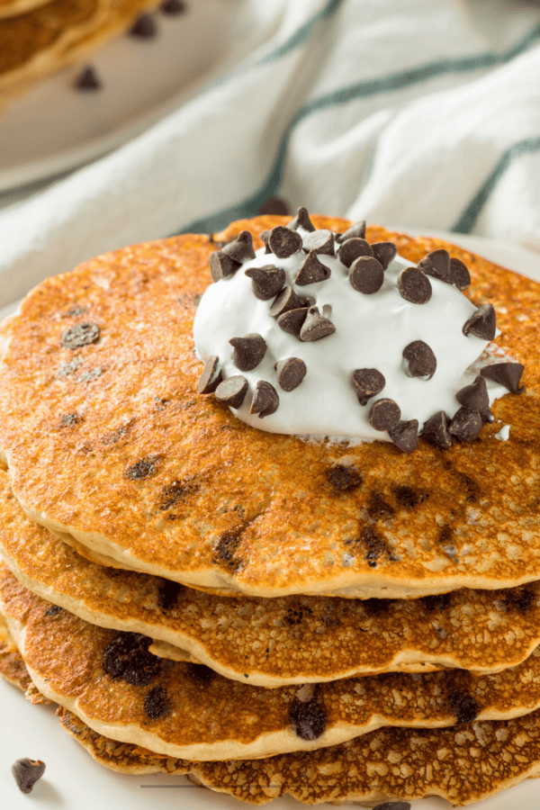 A stack of chocolate chip pancakes with whipped topping