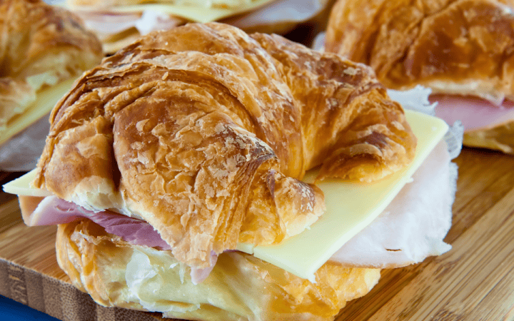 ham and cheese croissant sandwiches on a wooden cutting board