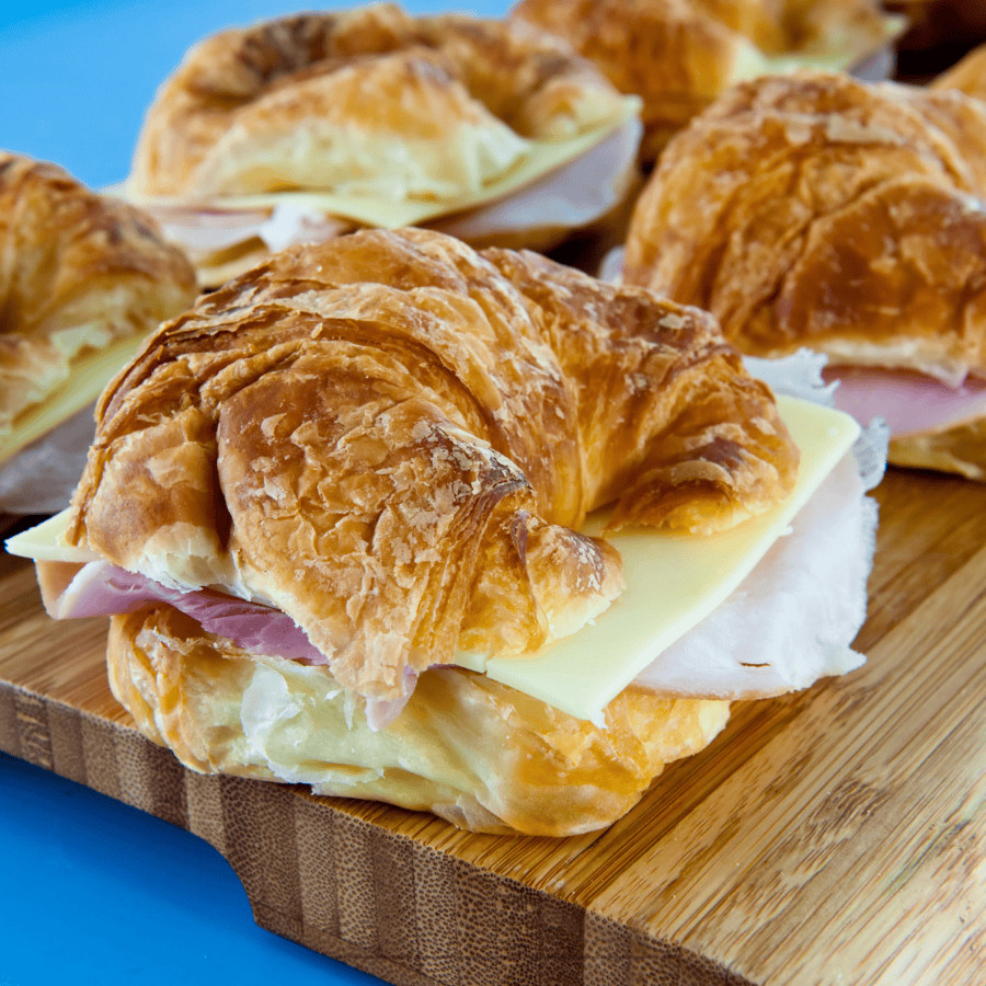 ham and cheese croissant sandwiches on a wooden cutting board