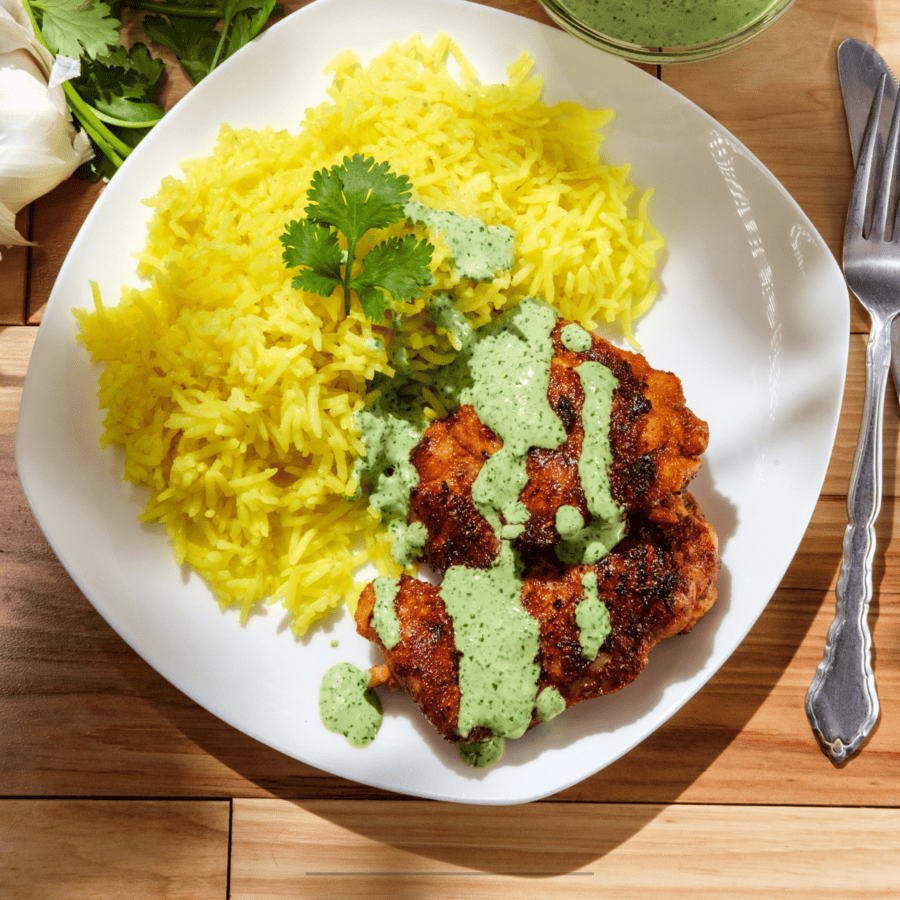 Overhead image of Peruvian Chicken Thighs with Aji Verde on a white plate with rice