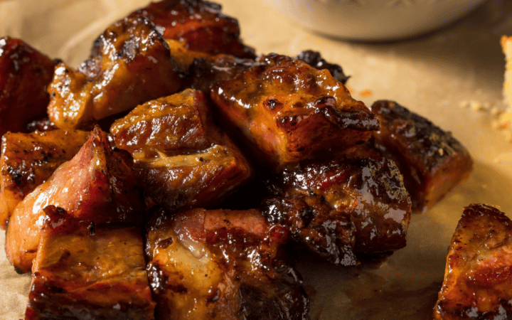 Pork Belly Burnt Ends on a wooden cutting board covered with parchment paper