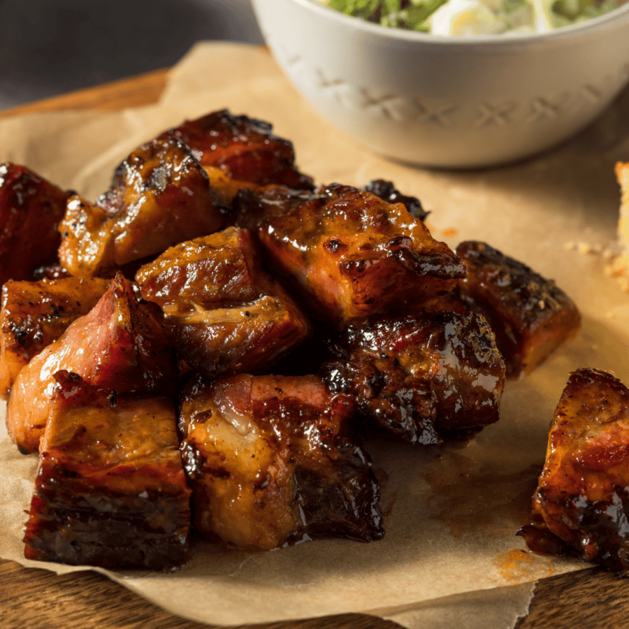 Pork Belly Burnt Ends on a wooden cutting board covered with parchment paper