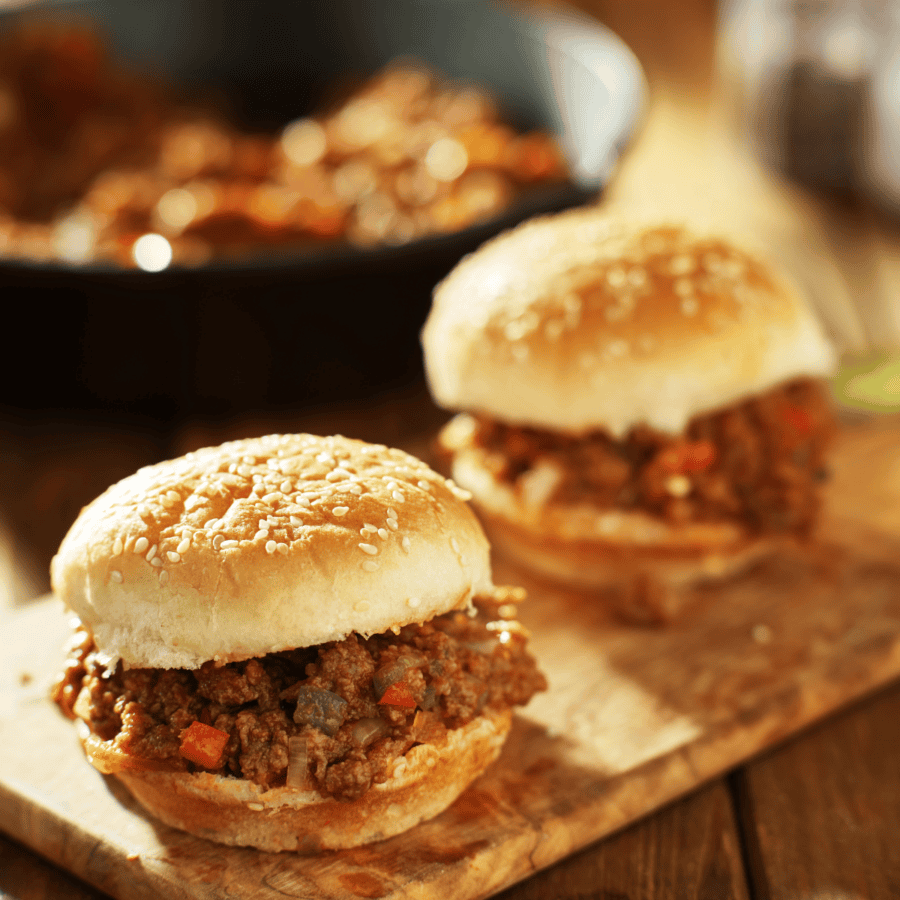 Two sloppy Joes on a wooden cutting board