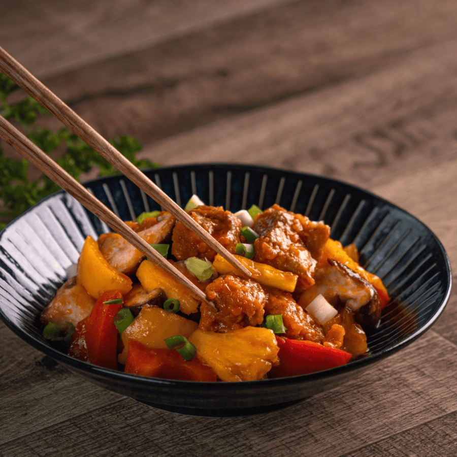 sweet and sour pork in a dish with chopsticks