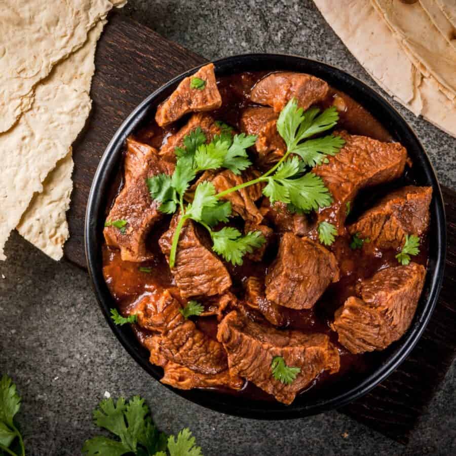 Overhead image of Chile Colorado in a black bowl with cilantro garnish