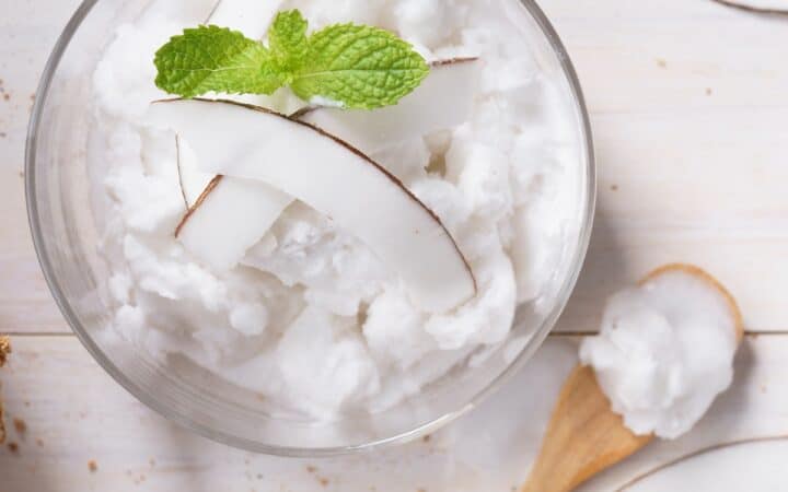 Overhead image of Coconut Ice Cream in a glass bowl with a wooden spoon