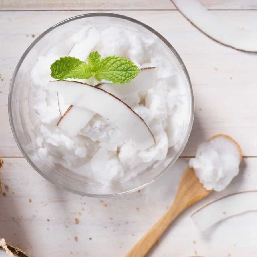 Overhead image of Coconut Ice Cream in a glass bowl with a wooden spoon