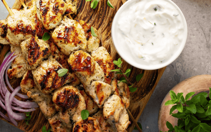 Overhead image of Greek chicken skewers on a wooden cutting board