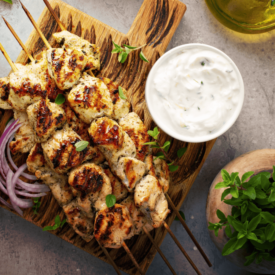 Overhead image of Greek chicken skewers on a wooden cutting board