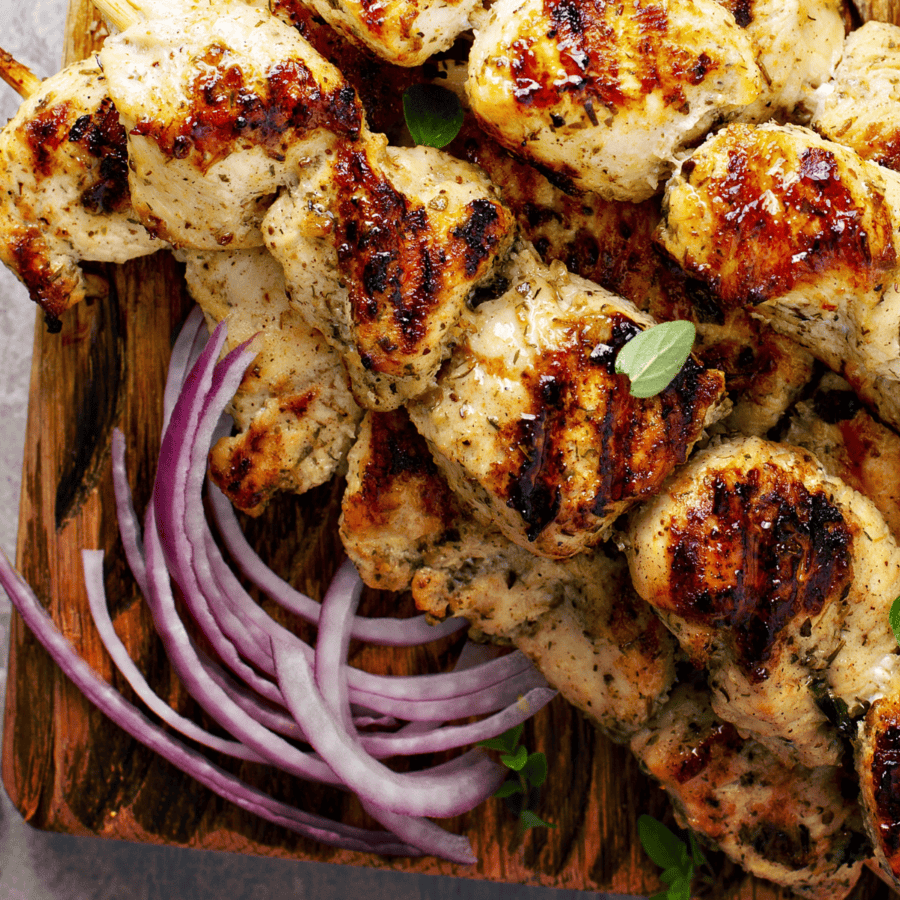 Close up image of Greek chicken skewers on a wooden cutting board