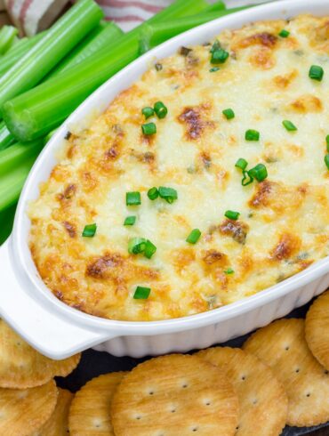 Overhead image of Maryland Crab Dip in a white oval baking dish surrounded by crackers and celery