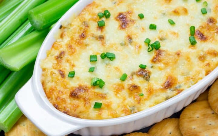 Overhead image of Maryland Crab Dip in a white oval baking dish surrounded by crackers and celery