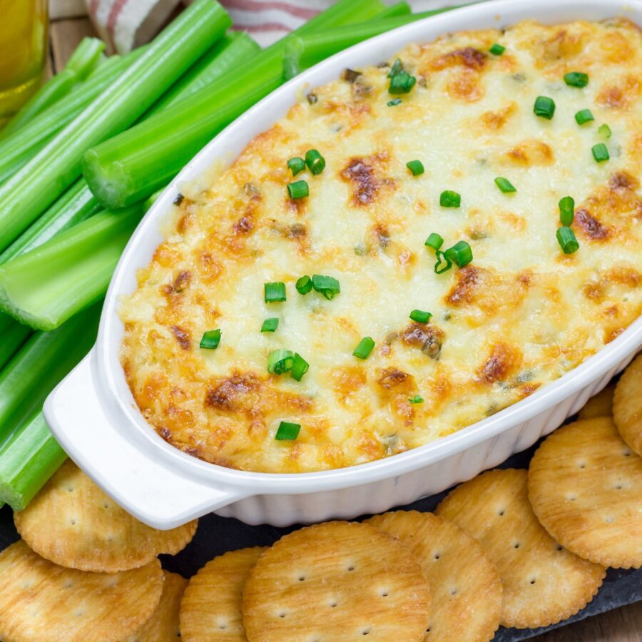 Overhead image of Maryland Crab Dip in a white oval baking dish surrounded by crackers and celery