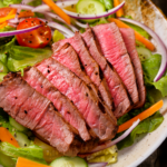 Overhead image of steak salad in a white bowl