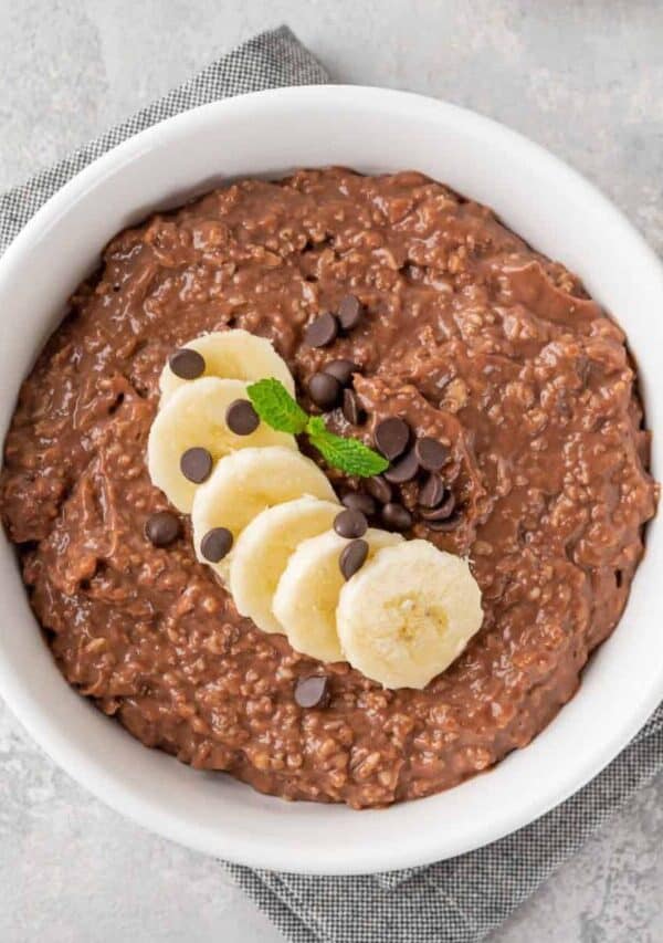 Overhead image of Chocolate Oatmeal in a white bowl with sliced bananas on top