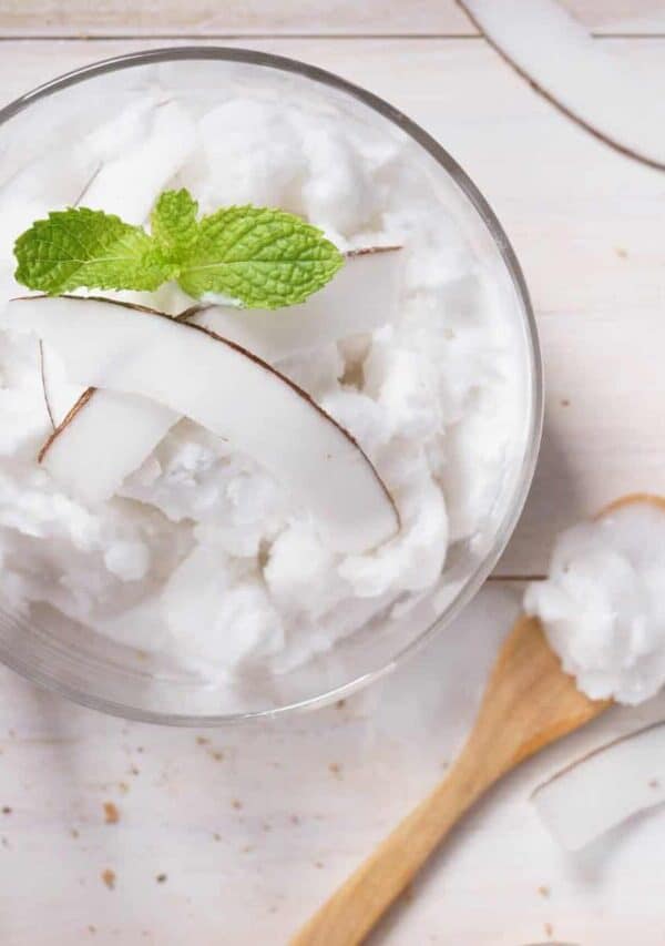 Overhead image of Coconut Ice Cream in a glass bowl with a wooden spoon