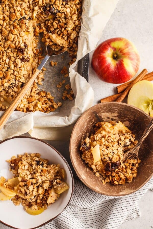 Overhead image of two servings of healthy apple crisp in bowls next to a baking dish