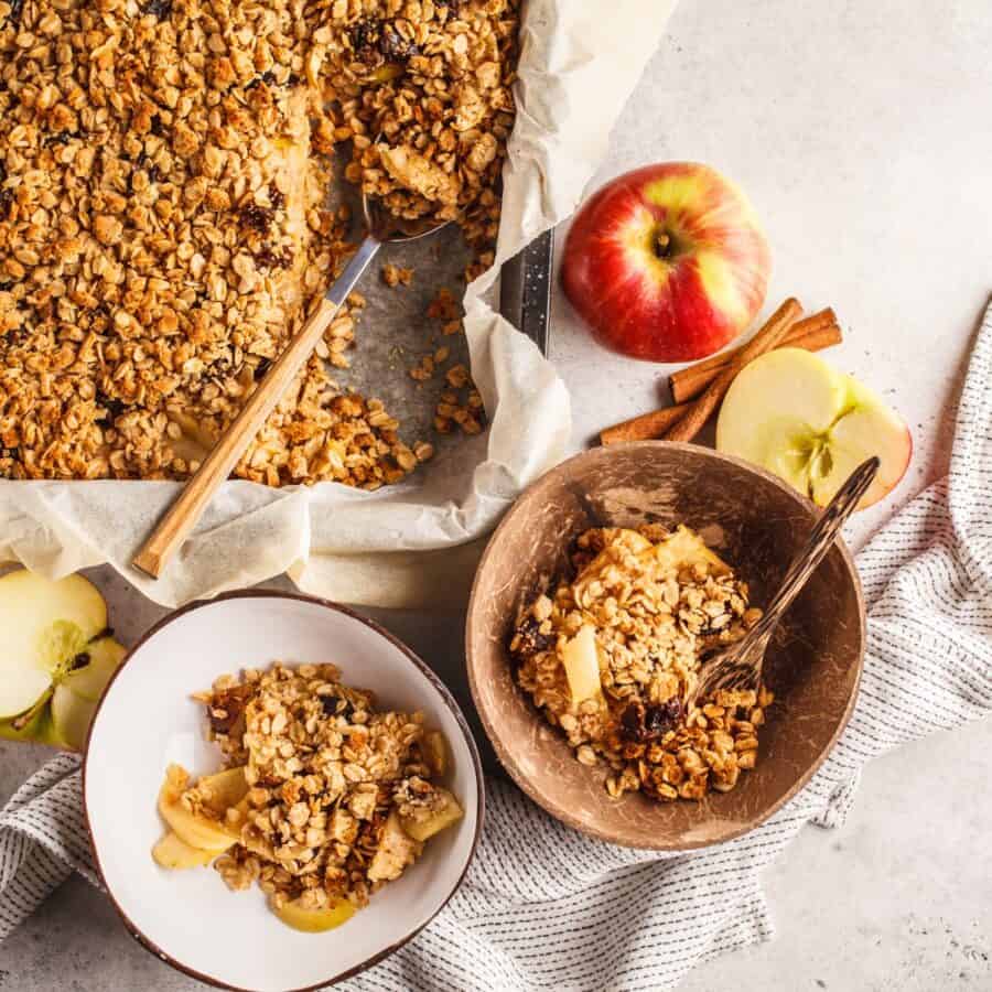 Overhead image of two servings of healthy apple crisp in bowls next to a baking dish