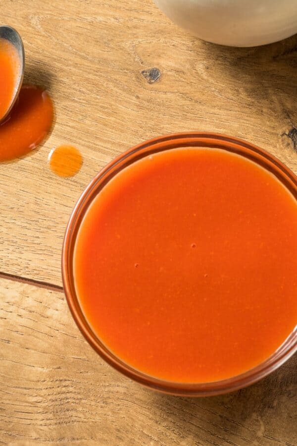 Overhead image of a glass bowl full of homemade buffalo sauce