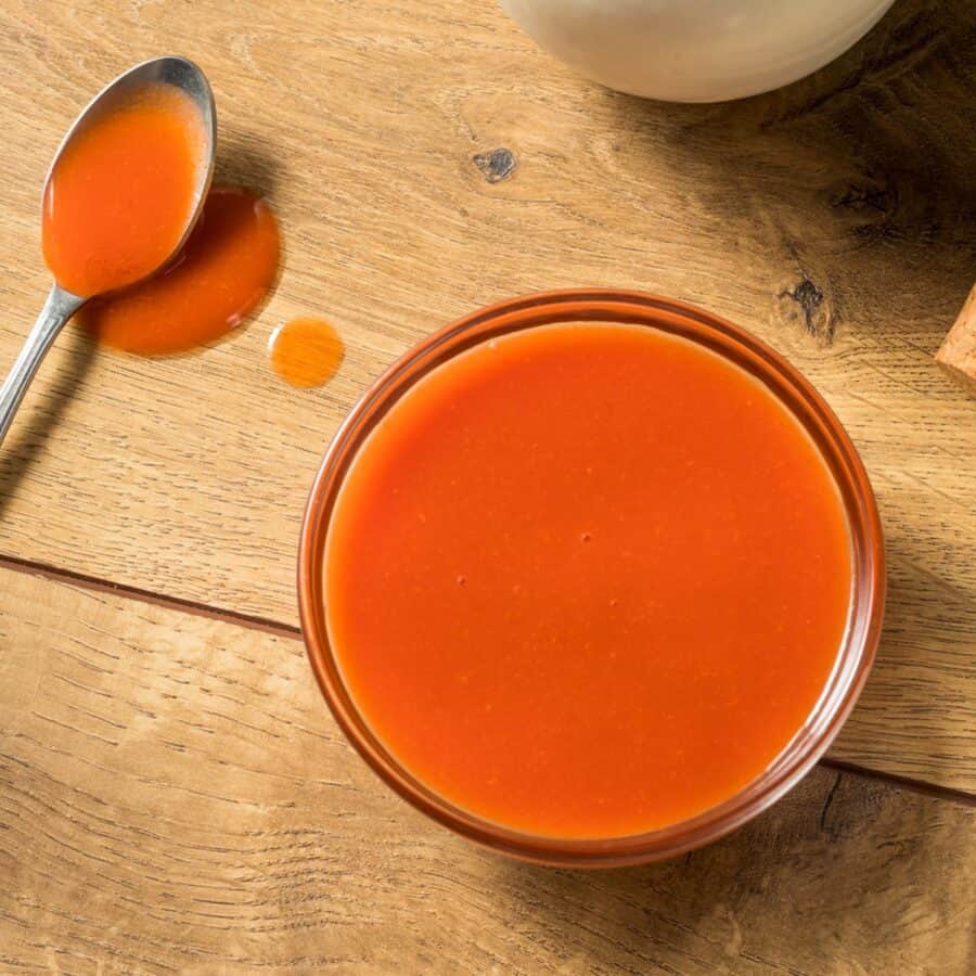 Overhead image of a glass bowl full of homemade buffalo sauce