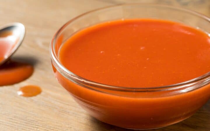 Close up image of homemade buffalo sauce with a spoon sitting next to it