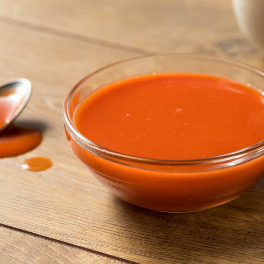 Close up image of homemade buffalo sauce with a spoon sitting next to it