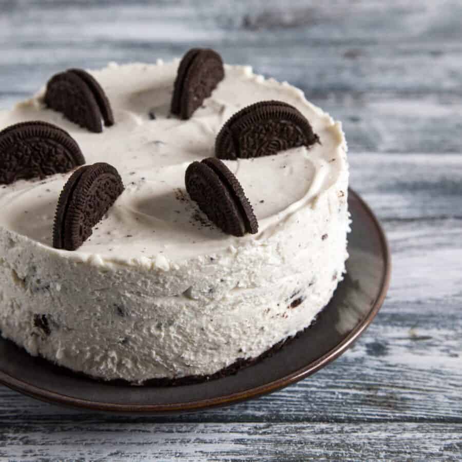 An Oreo Cheesecake on a dark cake stand 