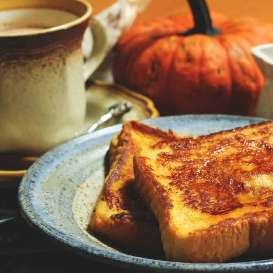 Close up image of Pumpkin French Toast on a plate with a cup of coffee in the background