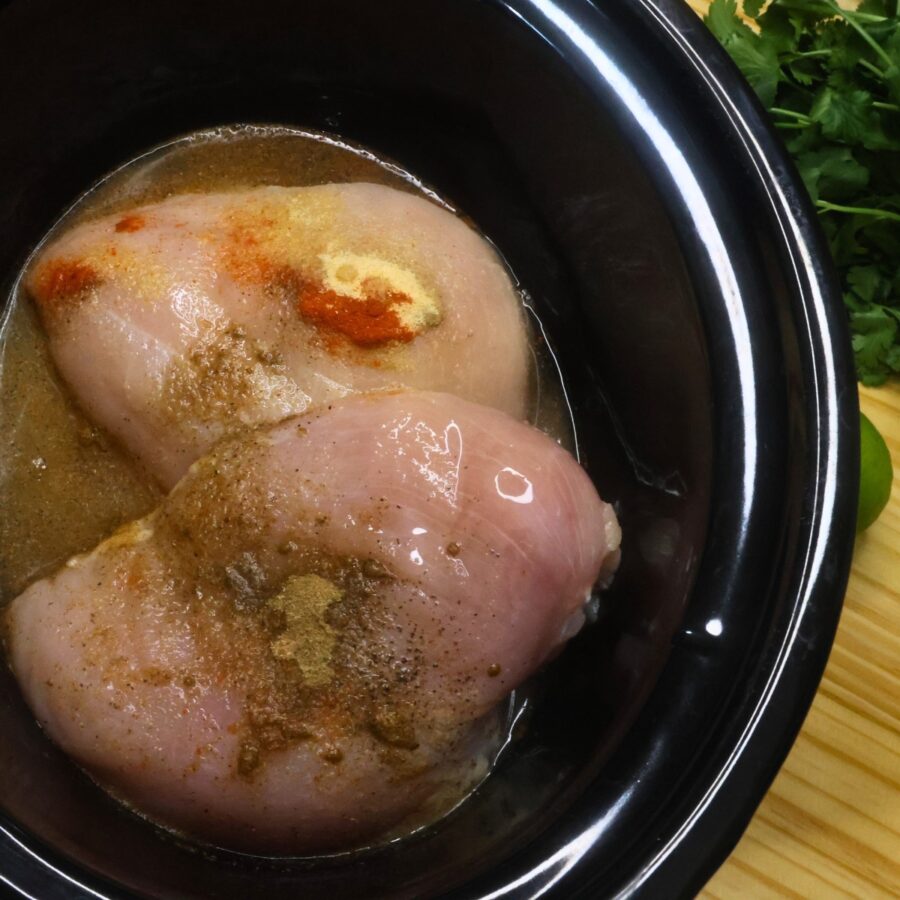 Chicken breasts in a slow cooker with spices, chicken broth, and lime juice