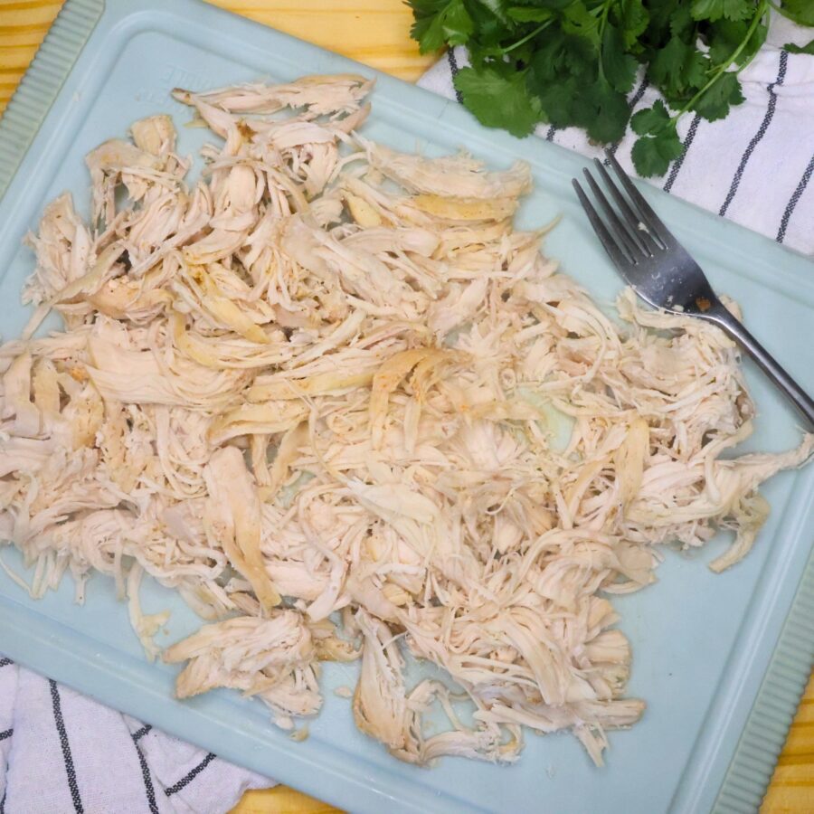 Shredded chicken breast for slow cooker street tacos on a blue cutting board