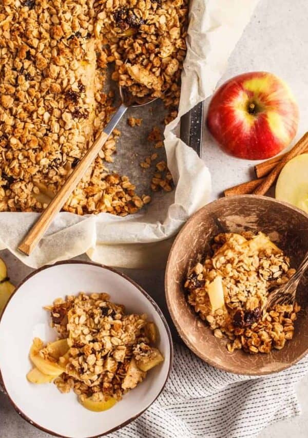 Overhead image of two servings of healthy apple crisp in bowls next to a baking dish