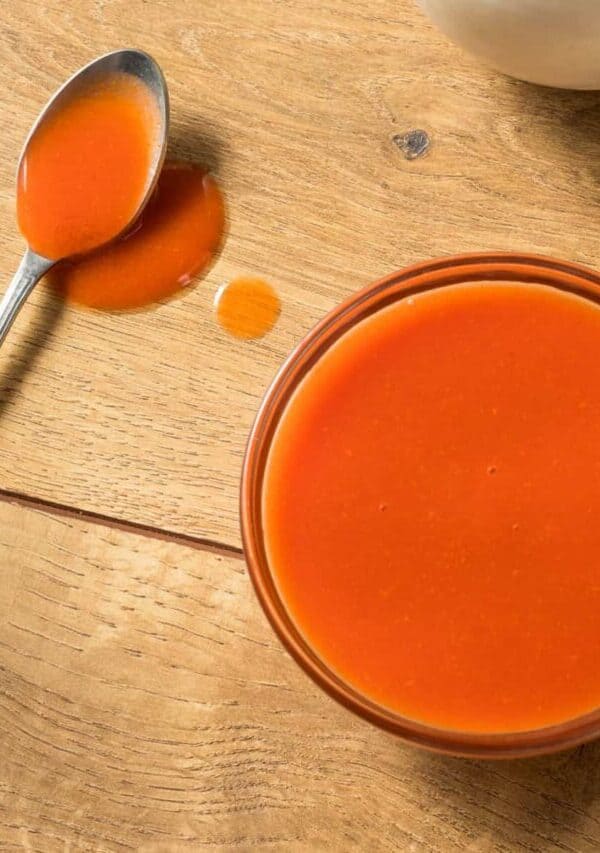 Overhead image of a glass bowl full of homemade buffalo sauce