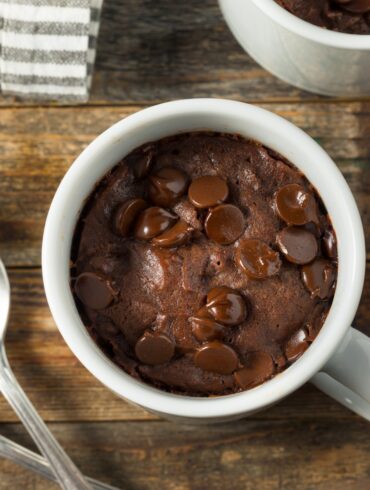 Overhead image of a brownie in a mug on a wooden surface