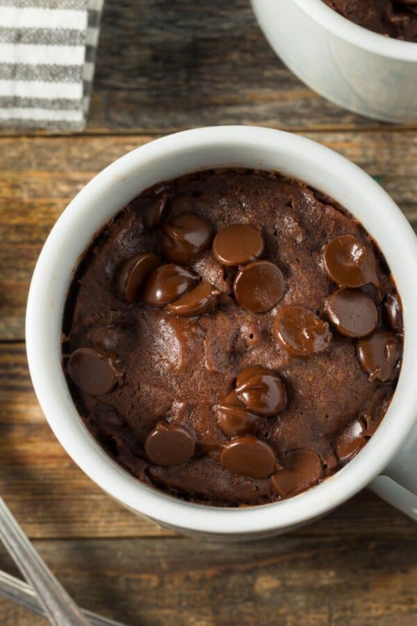 Overhead image of a brownie in a mug on a wooden surface