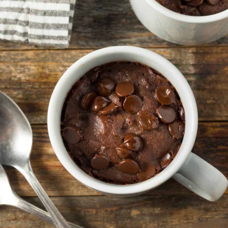 Overhead image of a brownie in a mug on a wooden surface