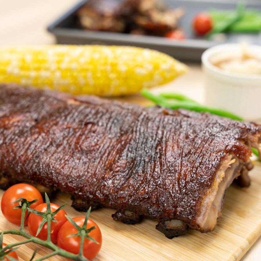 Close u image of baked ribs on a wooden cutting board