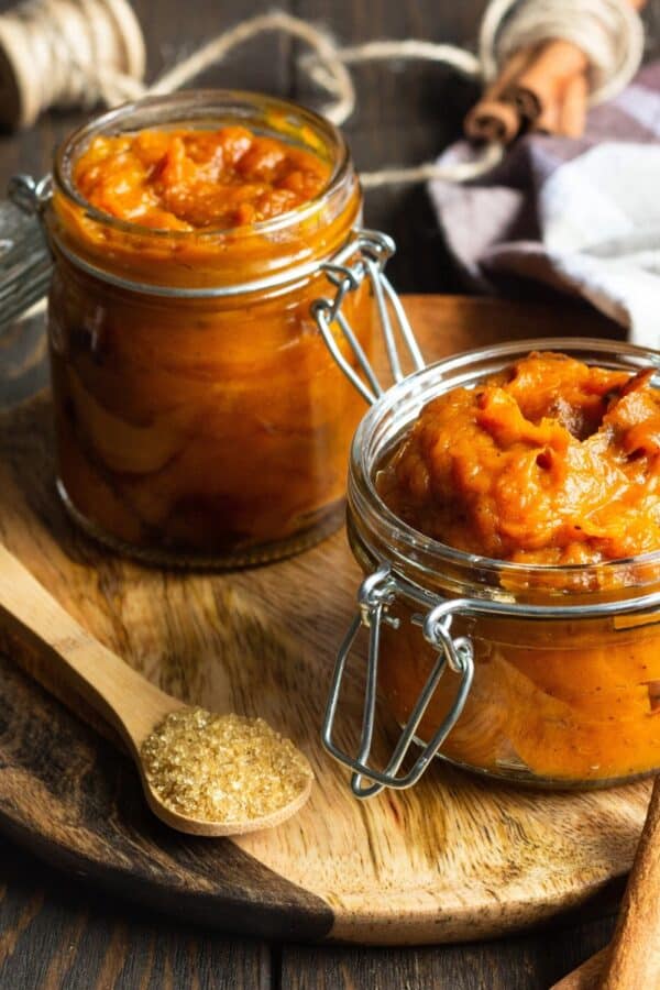 Two glass jars of Pumpkin Butter on a wooden cutting board