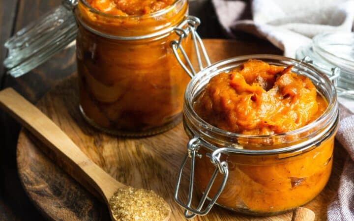 Two glass jars of Pumpkin Butter on a wooden cutting board