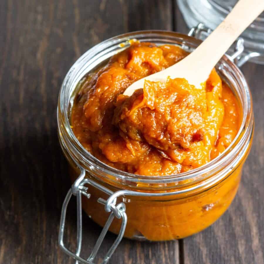 Clove up image of Pumpkin Butter in a glass jar with a spoon in it