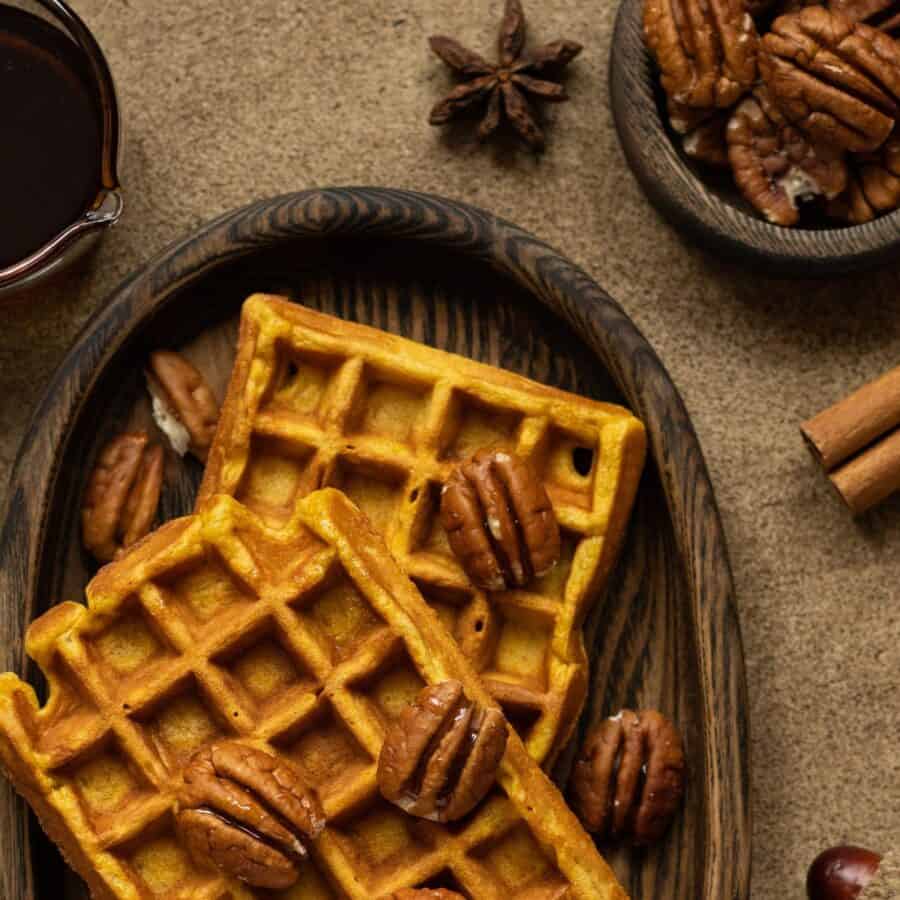 Close up image of pumpkin pecan waffles with pecans sprinkled over them