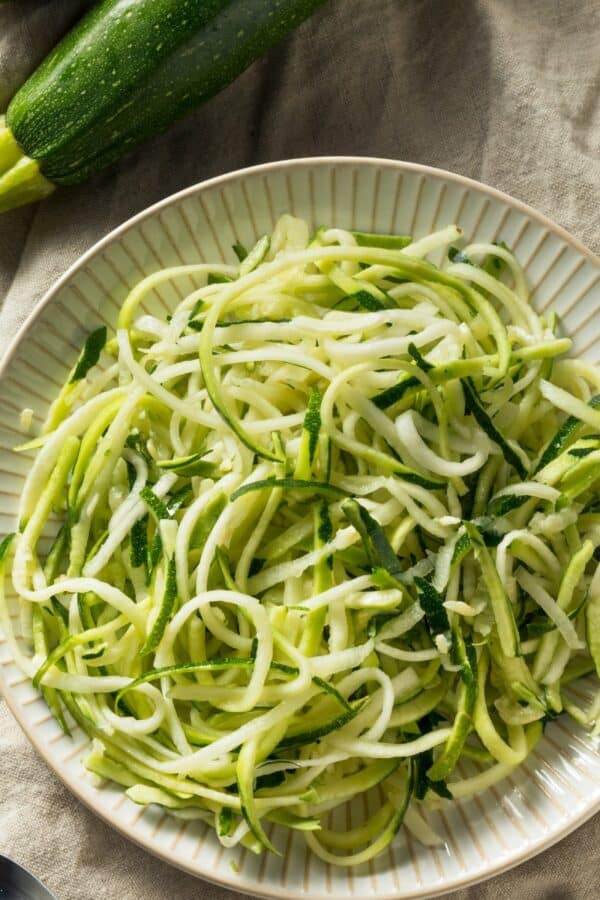 Overhead image of zucchini noodles on a cream colored plate