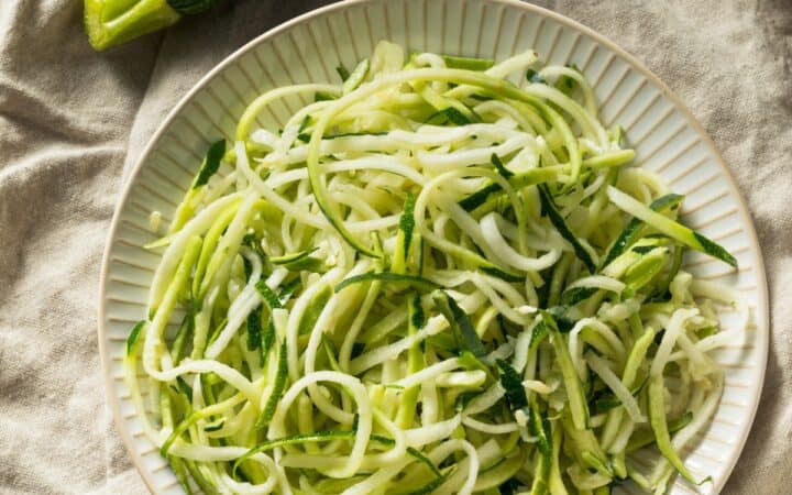 Overhead image of zucchini noodles on a cream colored plate