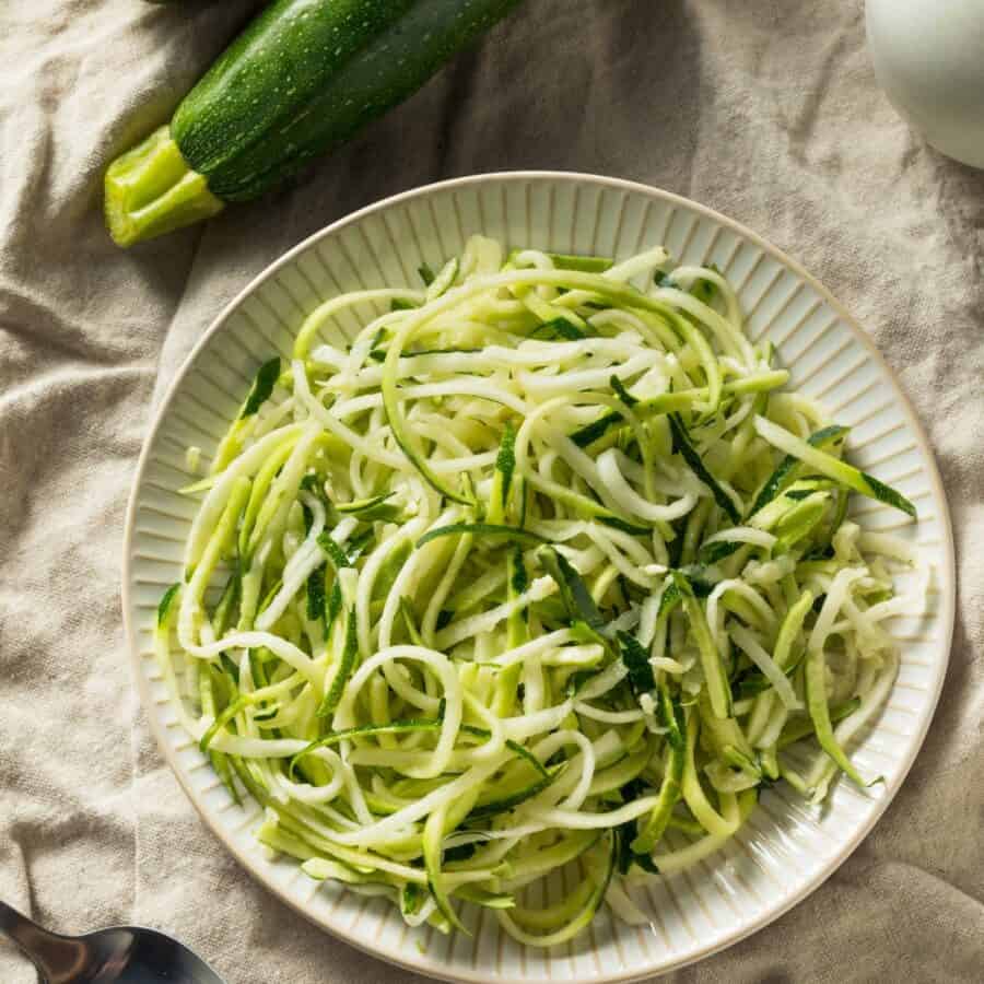 Overhead image of zucchini noodles on a cream colored plate